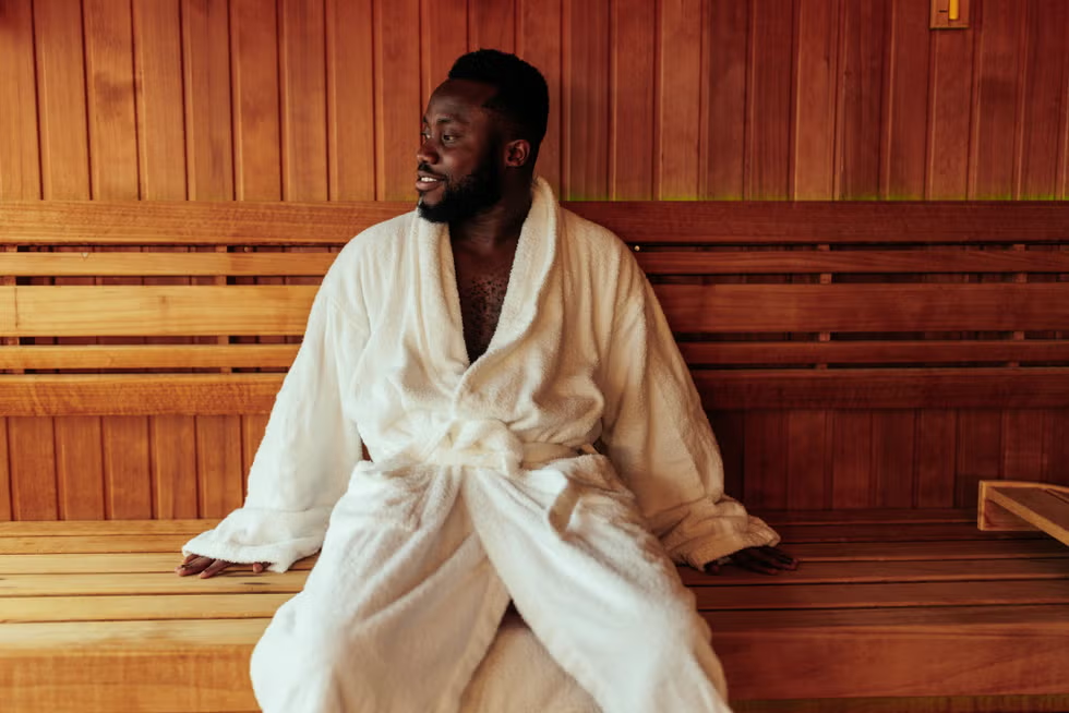 Man in white bathrobe enjoying peaceful sauna relaxation